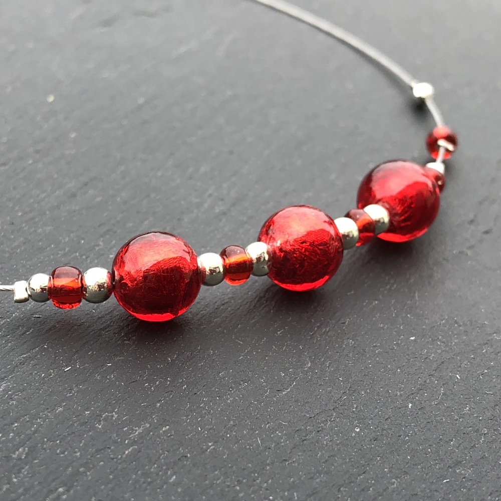 Ras de cou très lumineux, perles de couleur rouge intense